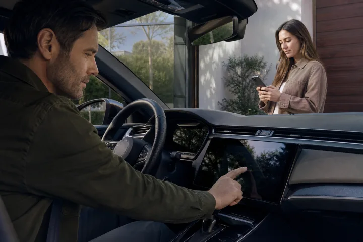 A person checks a car’s central screen and mobile app before handing it over to another owner.
