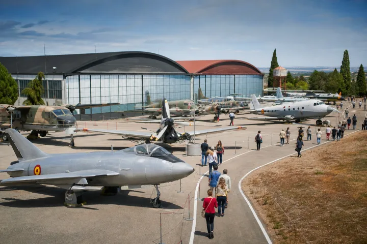 Historic aircraft displayed outdoors beside an aviation museum hangar