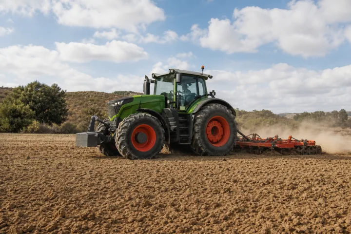 Agricultural tractor working with an implement in a crop field