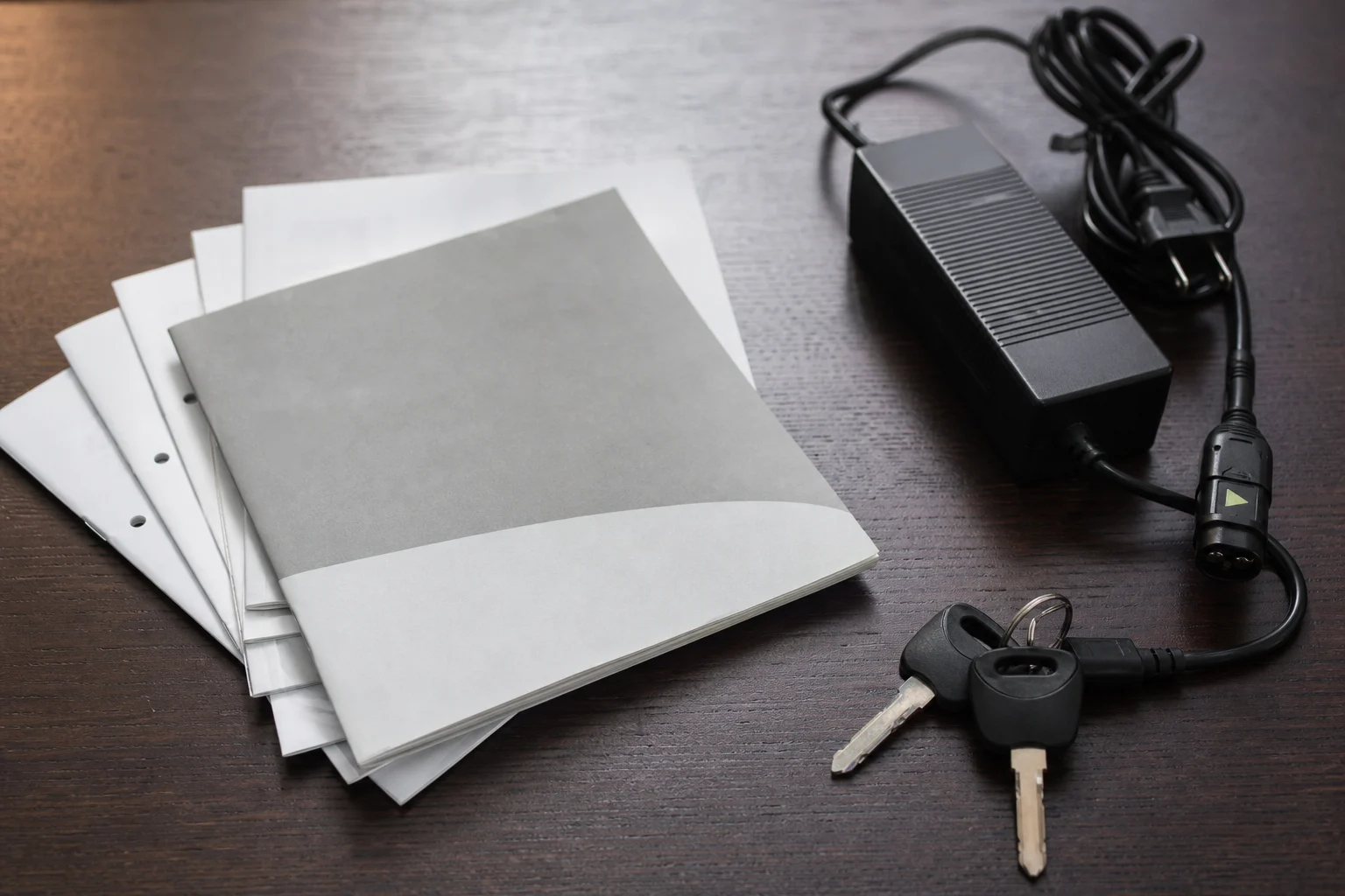 Documents, key, charger and cable for a used electric motorcycle on a table